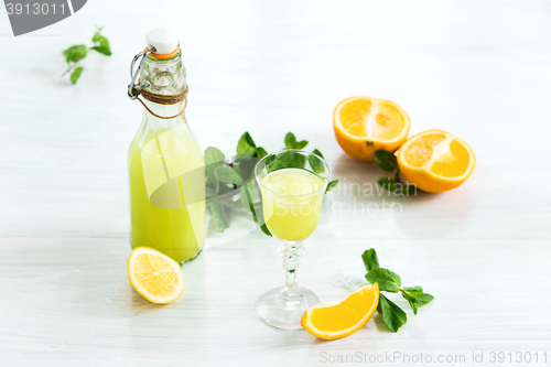 Image of Home orange liquor in a glass and fresh oranges on the white wooden background