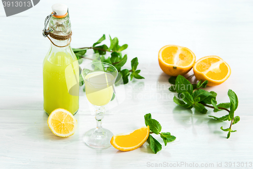 Image of Home orange liquor in a glass and fresh oranges on the white wooden background