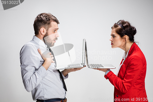 Image of The young businessman and businesswoman with laptops communicating on gray background