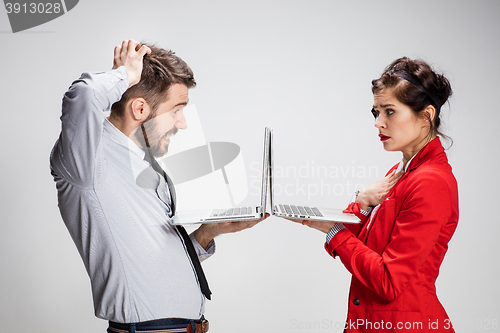 Image of The young businessman and businesswoman with laptops communicating on gray background