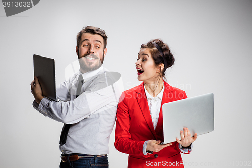 Image of The young businessman and businesswoman with laptops communicating on gray background