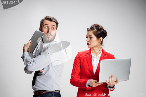 Image of The young businessman and businesswoman with laptops communicating on gray background