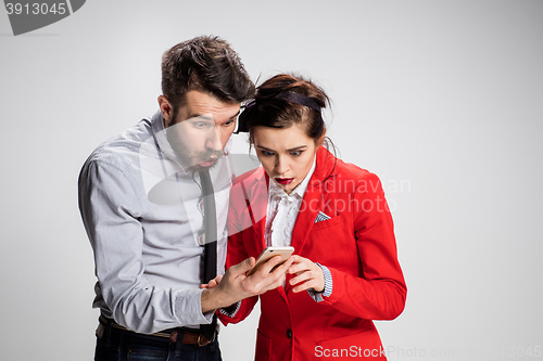 Image of Business concept. The two young colleagues holding mobile phone on gray background