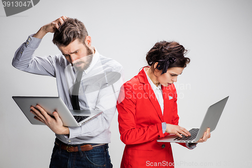 Image of The young businessman and businesswoman with laptops communicating on gray background