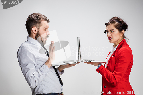 Image of The young businessman and businesswoman with laptops communicating on gray background