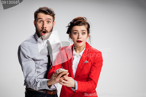 Image of Business concept. The two young colleagues holding mobile phone on gray background