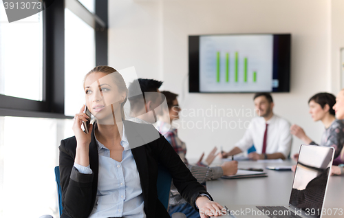 Image of business woman speeking on phone at office with team on meeting 