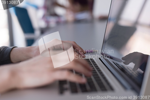 Image of close up of business womans hand typing on laptop with team on m