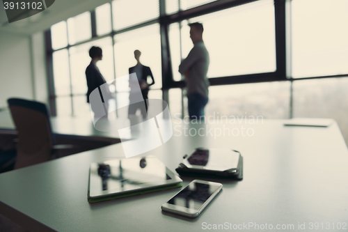 Image of close up of tablet, business people on meeting in background