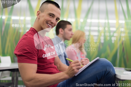 Image of male student taking notes in classroom
