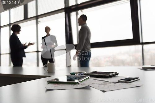 Image of close up of tablet, business people on meeting in background