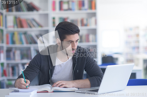 Image of student in school library using laptop for research