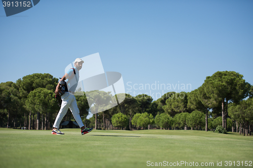 Image of golf player walking and carrying bag