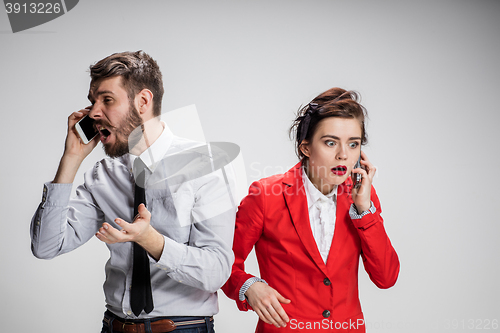 Image of Business concept. The two young colleagues holding mobile phones on gray background
