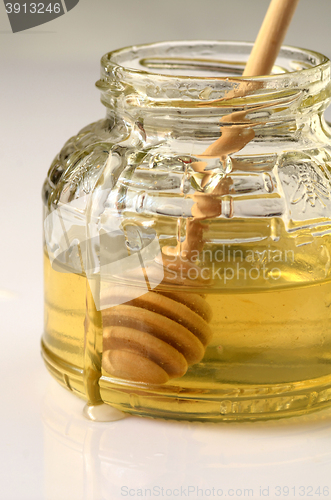 Image of honey and wooden dipper in a glass