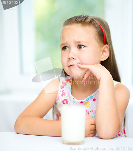 Image of Sad little girl with a glass of milk