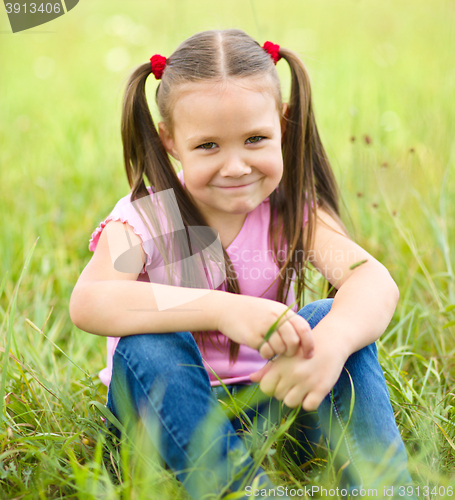 Image of Portrait of a little girl sitting on green grass