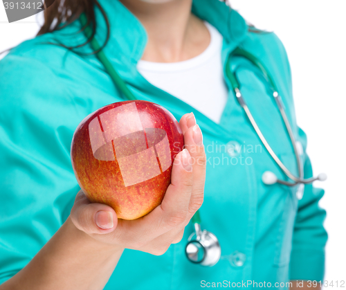Image of Young lady doctor is holding a red apple