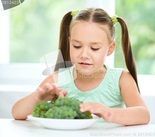 Image of Cute little girl is eating green grapes