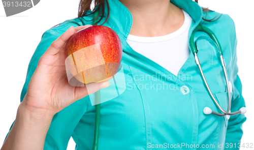 Image of Young lady doctor is holding a red apple