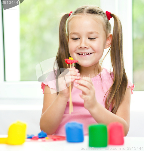 Image of Little girl is playing with plasticine