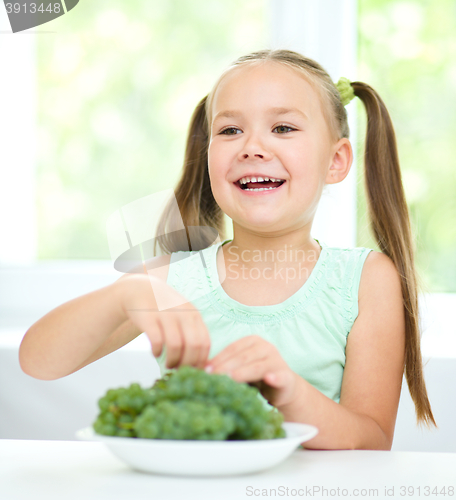 Image of Cute little girl is eating green grapes