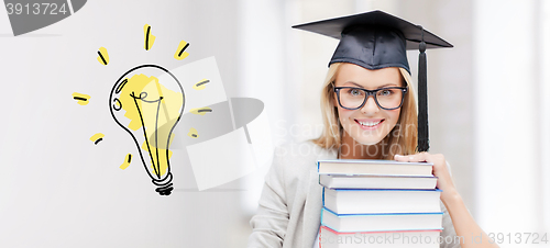 Image of happy student woman in mortarboard with books