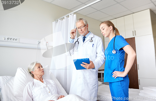 Image of doctor and nurse visiting senior woman at hospital