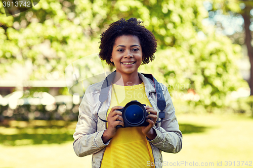 Image of happy african woman with digital camera in park