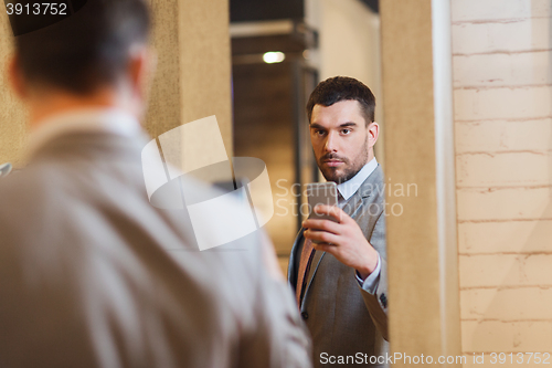 Image of man in suit taking mirror selfie at clothing store