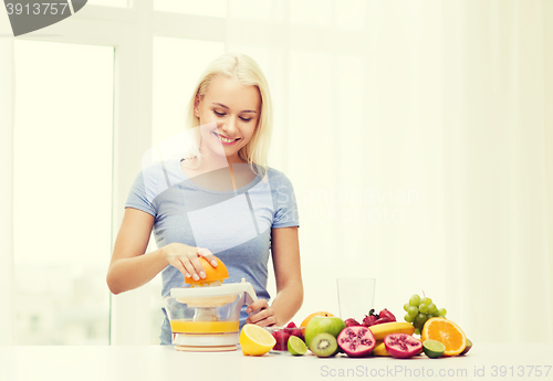 Image of smiling woman squeezing fruit juice at home
