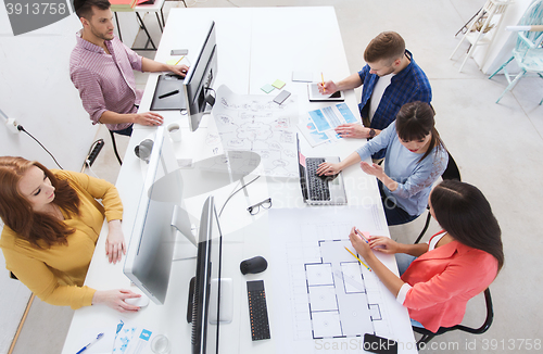 Image of creative team with computers, blueprint at office