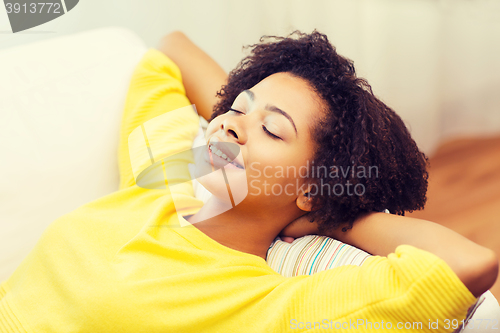 Image of happy african young woman relaxing at home