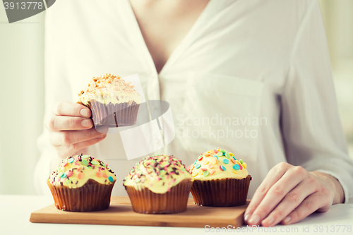 Image of close up of woman with glazed cupcakes or muffins