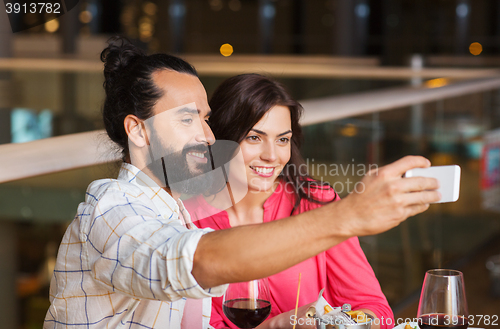 Image of couple taking selfie by smartphone at restaurant