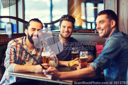 Image of friends taking selfie and drinking beer at bar