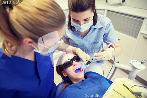 Image of female dentists treating patient girl teeth