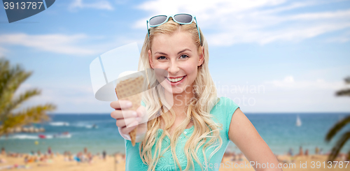 Image of happy young woman in sunglasses eating ice cream