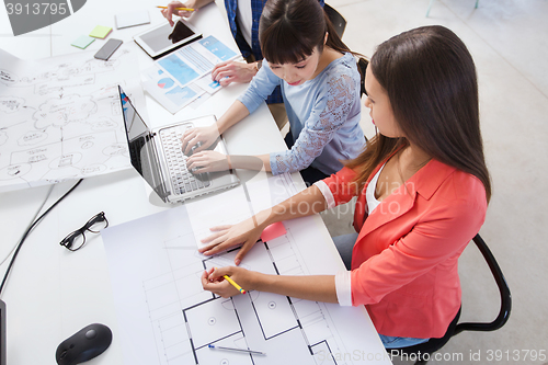 Image of creative team with laptop and blueprint at office