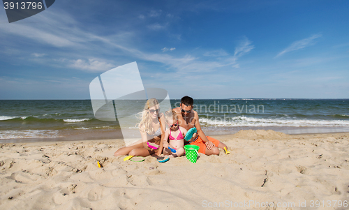 Image of happy family playing with sand toys on beach