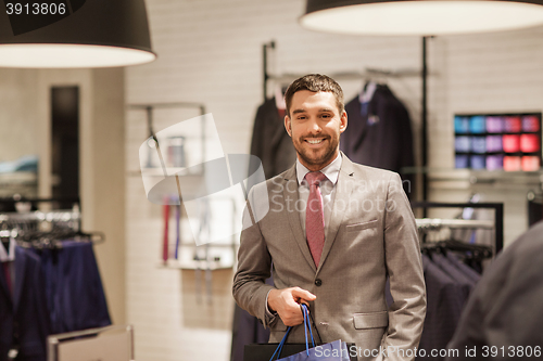 Image of happy man with shopping bags at clothing store