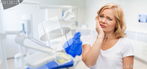 Image of unhappy woman suffering toothache at dental office