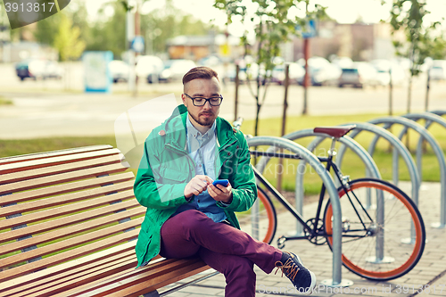 Image of happy young hipster man with smartphone and bike