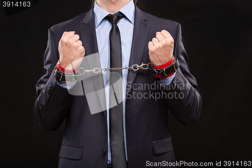 Image of man in a business suit with leather bound with handcuffs. sex Toys