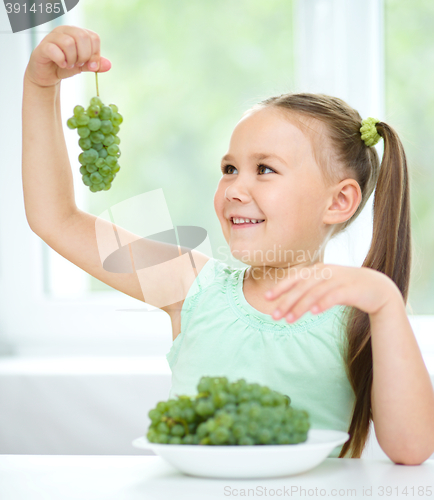 Image of Cute little girl is looking at green grapes