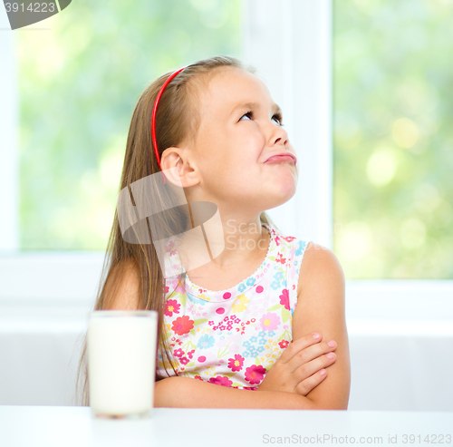Image of Sad little girl with a glass of milk