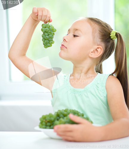 Image of Cute little girl is eating green grapes