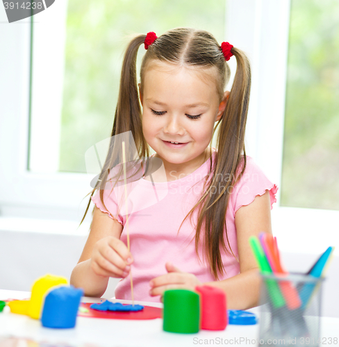 Image of Little girl is playing with plasticine