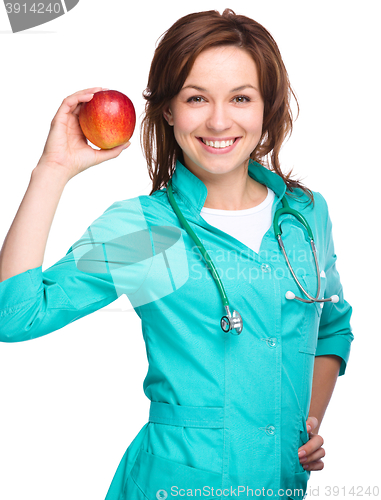Image of Young lady doctor is holding a red apple