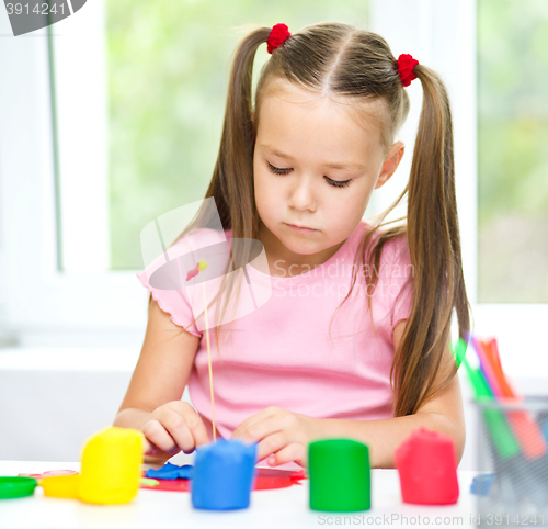 Image of Little girl is playing with plasticine